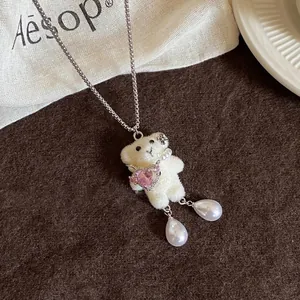 Vue rapprochée d'un pendentif ours en peluche avec gemme cœur rose et perles.