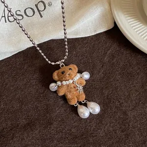 Gros plan d'un collier ours en peluche avec perles et breloque étoile sur fond marron