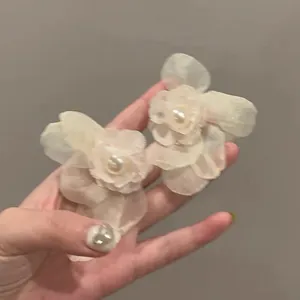 Detailed close-up of delicate mesh flower earrings with a pearl center in soft mint green.