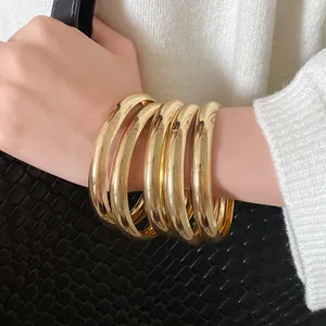 Nahaufnahme von glatten goldenen runden Armreifen am Handgelenk für Retro-Look