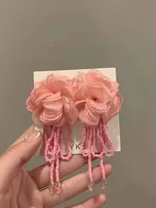 Detailed view of pink mesh flower earrings with long bead tassels on display card.