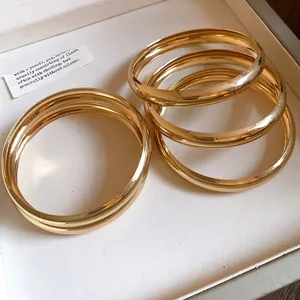 Nahaufnahme von glänzenden goldenen Armreifen in einer minimalistischen Schmuckschatulle.