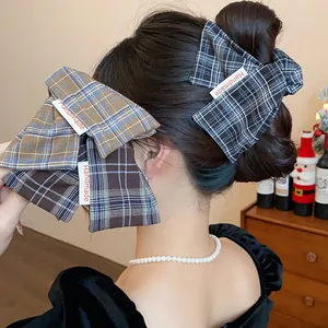 Detail view of plaid fabric bow hair claw clips with handmade label on a stylish bun.