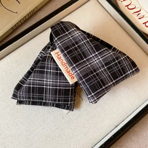 Close-up of a plaid fabric hair claw clip with a "Handmade" tag detail.