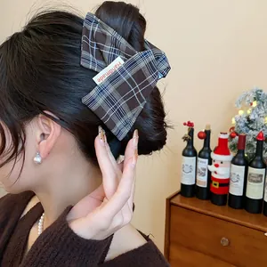 Close-up of a brown plaid fabric hair claw clip styled in a classic messy bun hairstyle