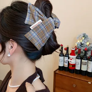 Detail of a plaid fabric shark hair clip with a "Handmade" label in brown and blue tones.