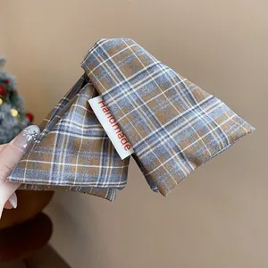 Detailed close-up of a plaid fabric triangle hair claw clip with a handmade label.