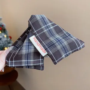 Detailed view of a dark brown plaid fabric triangle hair claw clip with a Handmade tag