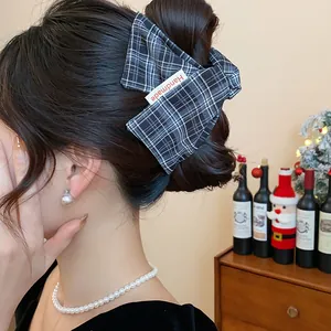 Close-up of a stylish black and white plaid fabric hair claw clip with handmade tag.