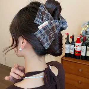Detail of plaid fabric hair claw clip with handmade tag on model's bun hair styles.