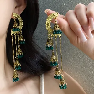 Detailed view of vintage ethnic tassel bell earrings with green beads and gold finish
