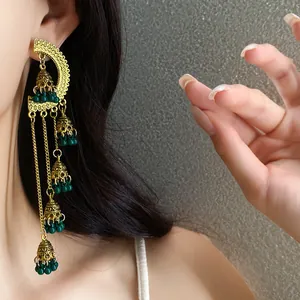 Close-up detail of vintage golden tassel earrings with dark green beads on model