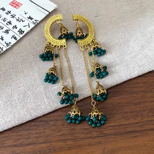 Close-up of vintage ethnic jhumka earrings with green bead tassels and gold geometric frames