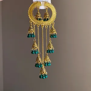 Detailed view of vintage palace style jhumka earrings with gold tassels and green beads