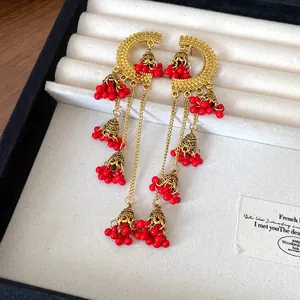 Detailed close-up of vintage ethnic bell tassel earrings featuring vibrant red beads.
