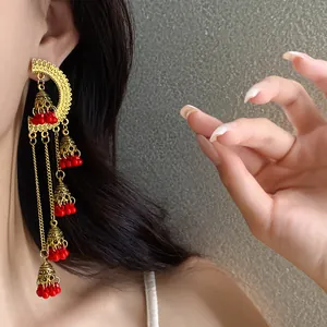 Elegant vintage ethnic style tassel bell earrings with red beads shown on a model's ear.