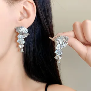 Close-up of elegant silver-colored multilayer fan-shaped drop earrings worn by a model