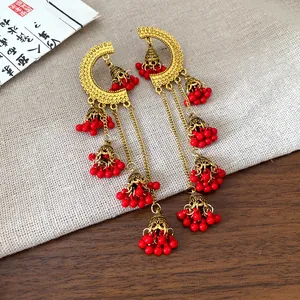 Detail view of ethnic retro bell tassel earrings with red beads on a linen background.