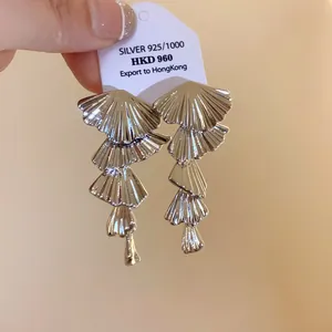 Macro detail of elegant silver-toned multi-layered fan-shaped dangling earrings on a tag