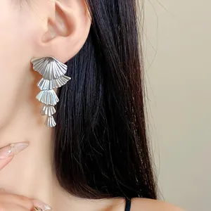 Detailed close-up view of elegant silver layered fan-shaped earrings worn by a model.
