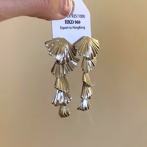 Detail shot of layered fan-shaped gold earrings with a sparkling metallic finish.