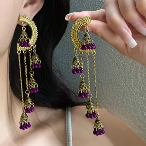 Close-up of vintage palace style gold tassel earrings with purple beads and bells.