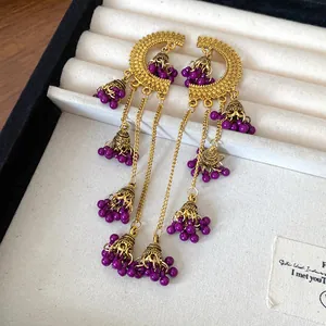 Detailed view of vintage ethnic style earrings with purple beads and bell tassels