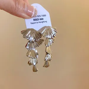 Macro view of multi-layered silver fan-shaped drop earrings showing metallic luster