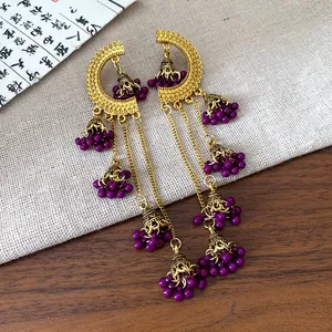 Detailed shot of vintage gold-finished dangle earrings with purple beads and elegant tassels