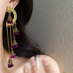 Close-up detail of retro palace style golden tassel bell earrings with purple beads