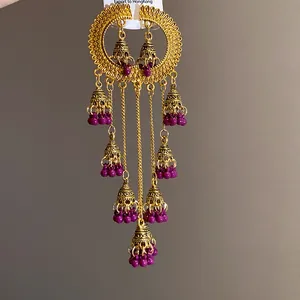 Detailed view of vintage ethnic gold-tone earrings with purple beads and bell tassels