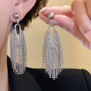 Close-up of silver-toned beaded tassel earrings showing metallic texture and drape detail.