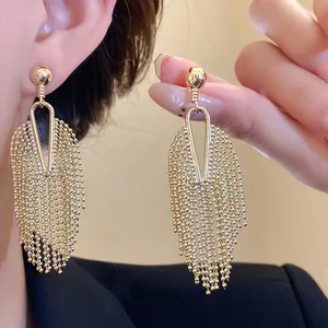 Macro view of elegant gold tassel drop earrings showing detailed fringe texture