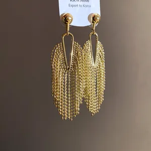 Macro view of gold-tone beaded tassel earrings with a stylish geometric drop shape.