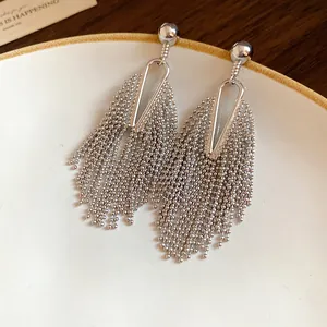 Detailed macro shot of silver tassel drop earrings with beaded fringe on a white plate