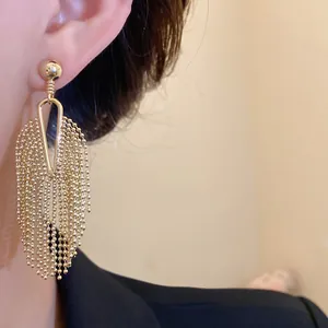 Close-up of gold beaded chain tassel earrings on a model showing luxury detail