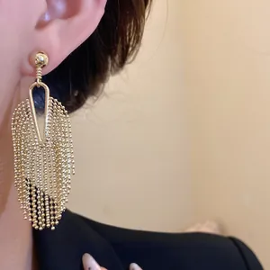 Close-up of elegant gold bead fringe tassel earrings worn on ear