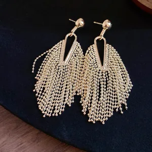 Close-up of elegant gold beaded chain tassel earrings on black velvet