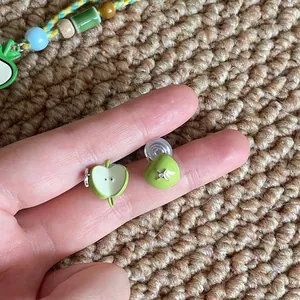 Gedetailleerde macro-opname van groene appel hars clip-on oorbellen in de hand