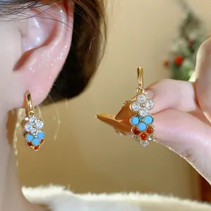 Close-up detail of gold-plated tassel earrings with colorful flower-shaped zircon stones