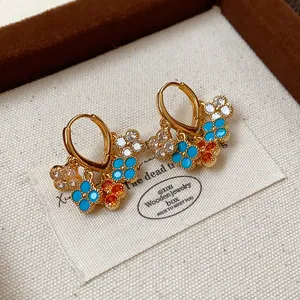 Close-up of gold-plated hoop earrings with colorful zircon flower charms