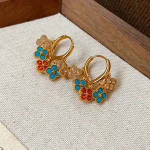 Close-up of elegant gold-plated flower earrings with colorful zircon stones and clover design