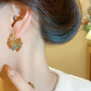 Close-up of vintage gold-plated zircon flower earrings worn by a model in a warm setting
