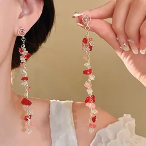 Detailed shot of elegant long pink and red crushed stone tassel earrings worn for scale
