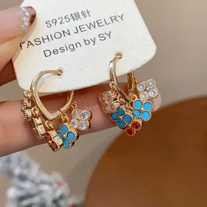 Close-up of elegant gold plated hoop earrings with colorful zircon flower tassels