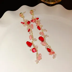 Close-up of pink and red crushed stone tassel earrings with elegant golden accents