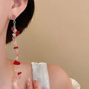 Detailed shot of long tassel earrings with pink rhinestones and irregular red stones on model