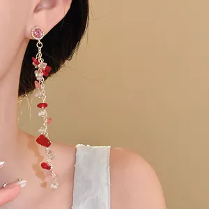 Close-up detail of elegant long tassel earrings with pink and red gravel stones