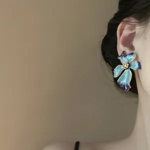 Primer plano detallado de pendientes de flores azules con acabado de gota de aceite