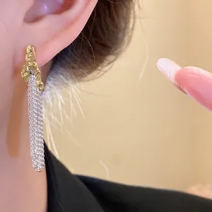 Elegant gold and silver tone pleated C-shaped earrings with metallic fringe tassels